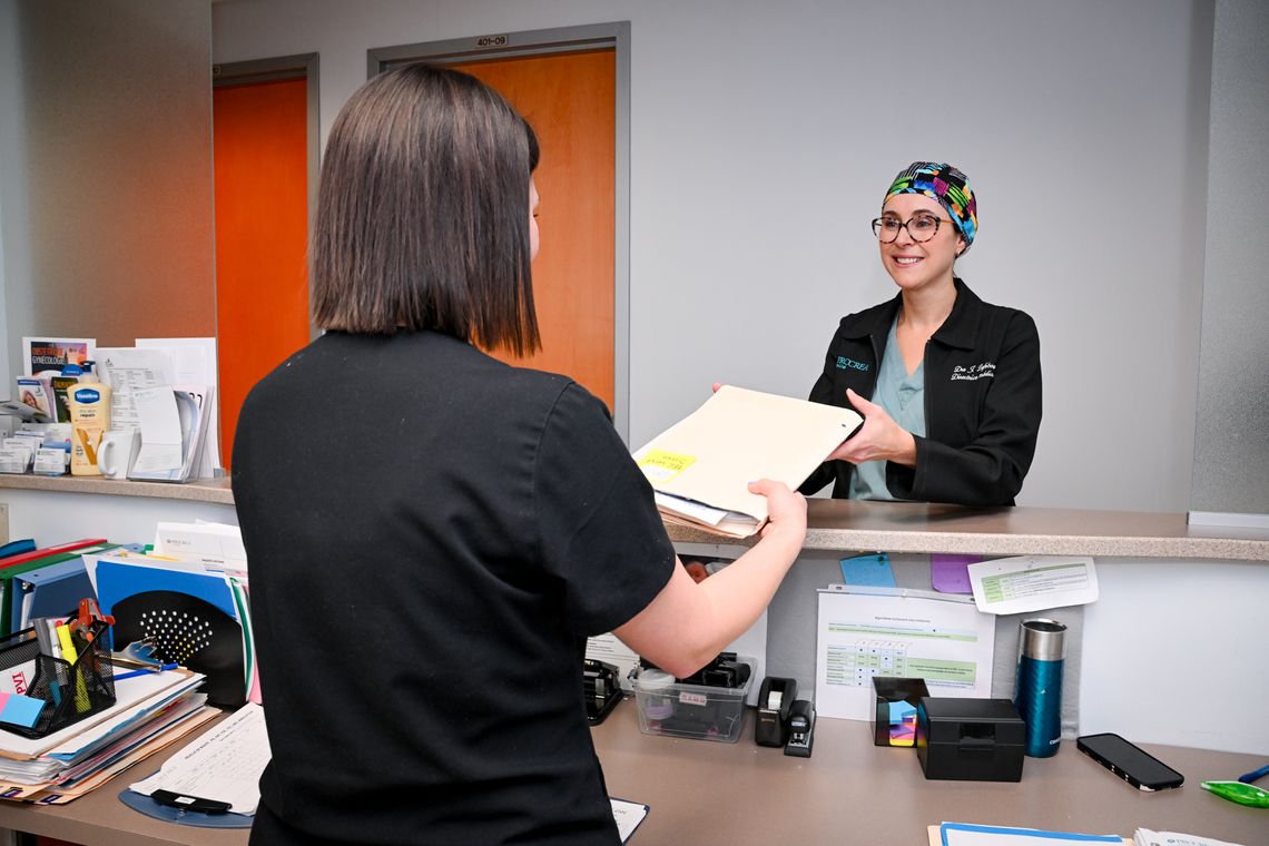 receptionist handing file to a doctor